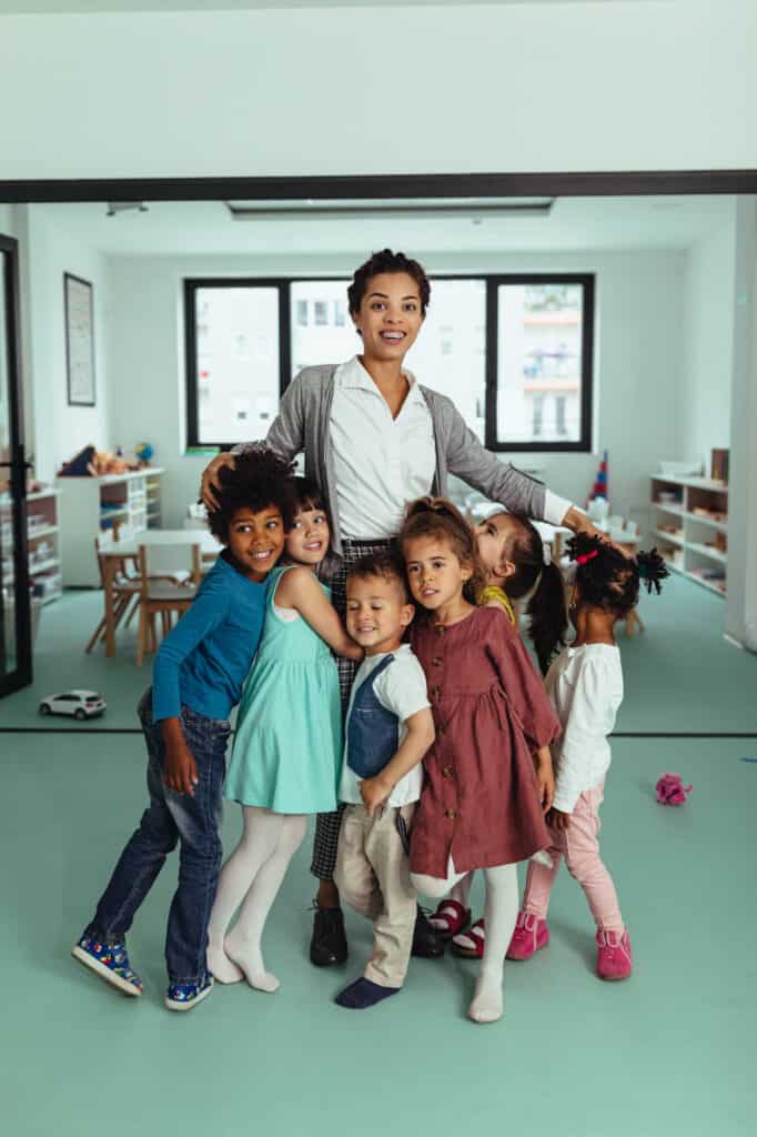 Enseignante avec enfants dans une salle de classe lumineuse et colorée.